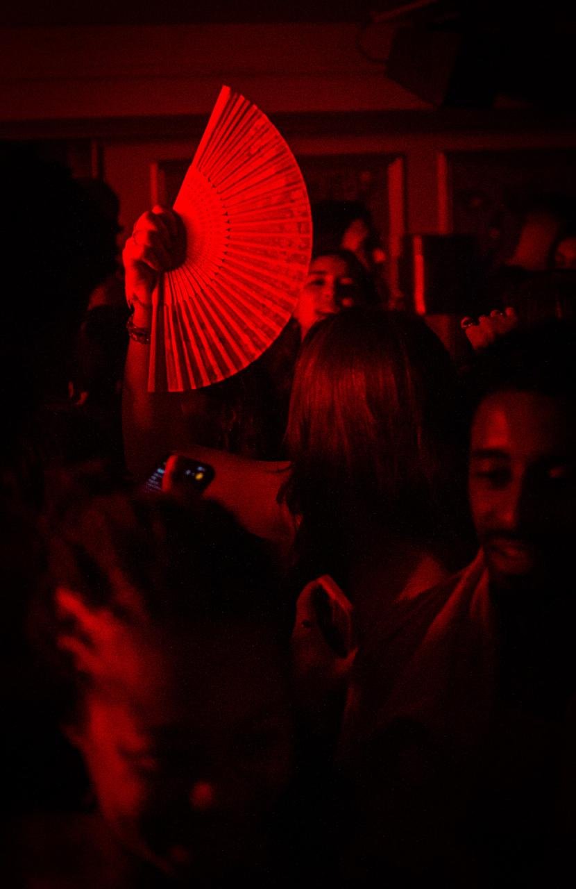 A folding fan held above the crowd beneath red club light